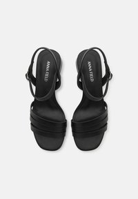Sandali neri con tacco dal design elegante. Presentano due larghe cinghie trasversali sul piede e una cinghia alla caviglia regolabile. Texture liscia.