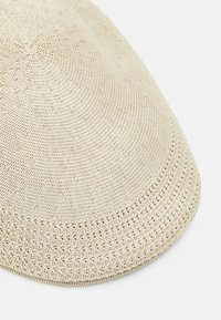 Virkat beanie i beige med ett strukturerat mönster. Har en cirkulär design och en något upphöjd kant för en tajt passform.