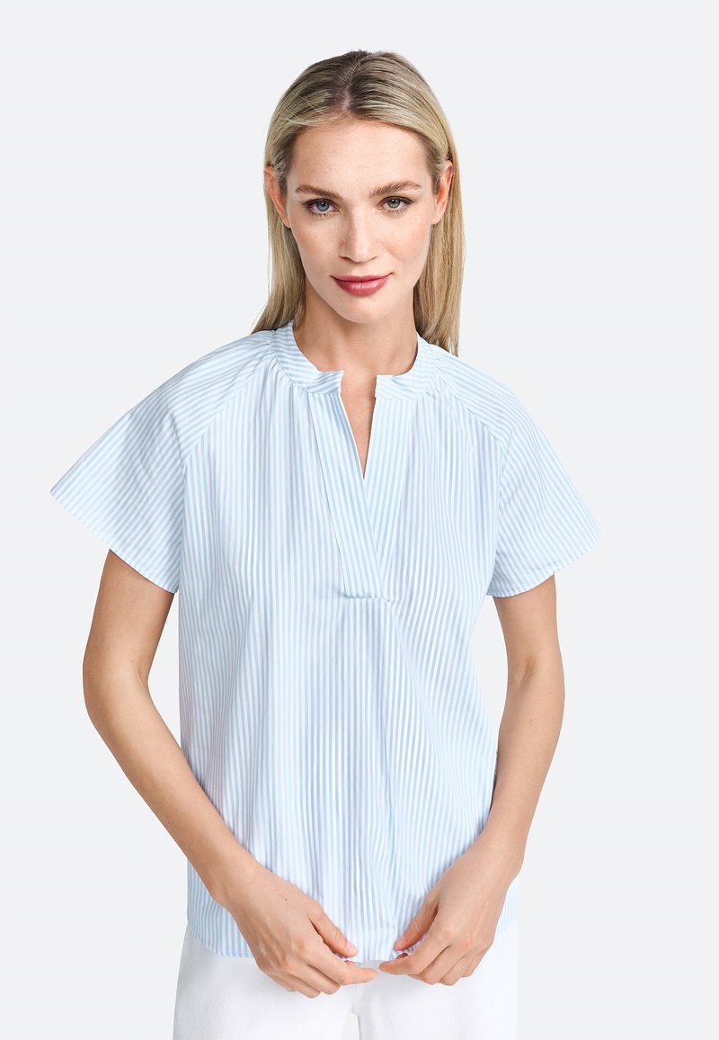 Camicia azzurro chiaro a maniche corte con strisce bianche verticali, caratterizzata da un colletto alla coreana e un'apertura a chiave sul davanti. Tessuto dalla consistenza liscia.