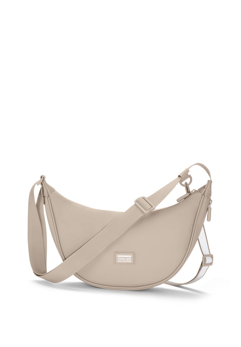 Borsa a tracolla beige realizzata in materiale sintetico liscio, con una forma rotonda, tracolla regolabile e un patch logo rettangolare sul davanti.