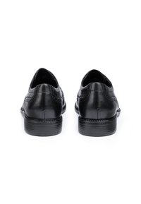 Scarpe in pelle nera con una superficie liscia, punta arrotondata e cuciture dettagliate sulla tomaia. Tacco basso impilato con suola in gomma.