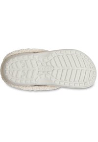 Witte rubberen zool van een slipper met een gestructureerd patroon en een zachte, crème-kleurige fleece voering rondom de rand.