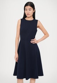 Tmavomodré šaty bez rukávov s priliehavým živôtikom a rozšírenou sukňou, vyrobené z hladkej, elastickej látky. Minimalistický dizajn s okrúhlym výstrihom.