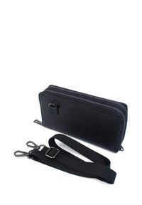 Black leather zip-around wallet with detachable adjustable black fabric strap and metal clasps on white background.