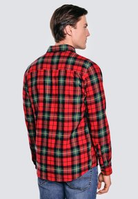 Czerwona i czarna koszula flanelowa w kratę z kołnierzykiem na guziki i długimi rękawami, z kontrastującymi zielonymi liniami w wzorze.