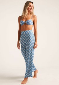 Bikini azul de dos piezas que presenta un top estampado con copas con aros y una falda larga a juego con diseños florales. Textura suave.
