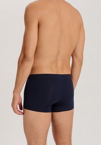 Mörkblå boxershorts i stretchtyg med en åtsittande passform, elastiskt midjeband och sömlös design för komfort.