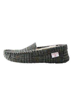 Zapatilla mocasín para hombre tipo slip-on con exterior de tela tweed gris y forro interior de forro polar blanco, con detalles cosidos y una pequeña etiqueta roja de la marca.