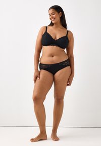 Bralette nera in pizzo con spalline regolabili e culotte in stile bikini abbinate, con bordo in pizzo lungo l'elastico e una finitura liscia.
