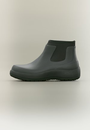Botte de pluie cheville gris foncé avec panneaux latéraux élastiques et semelle épaisse sur fond neutre