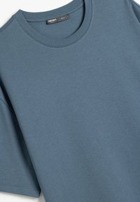 Blå bomulds t-shirt med korte ærmer, rund halsudskæring og en blød tekstur. Inkluderer et mærke nær kraven.