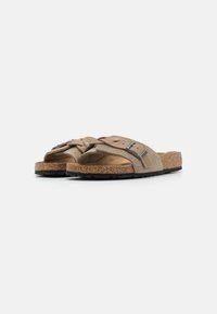 Sandali a scivolo in suede marrone con due fasce larghe, dettagli con fibbie argentate, plantare in sughero e suola nera testurizzata.