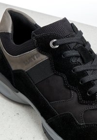 Černá teniska kombinující semiš a textilní materiály, strukturovaný design, strukturovaný povrch a gumová podrážka s dekorativními prvky.