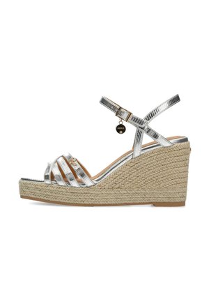 Sandalo a wedge metallizzato argento con cinturini incrociati, tacco avvolto in juta, cinturino alla caviglia regolabile e dettaglio decorativo con charm.