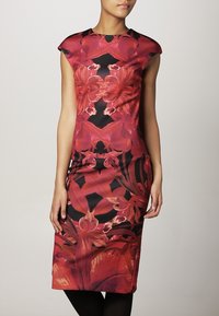 Robe moulante à motif floral rouge et noir. Manches courtes en forme de capuchon, longueur au genou, texture lisse et silhouette ajustée.