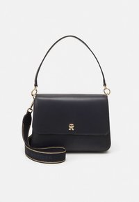 Navy leather handbag with a structured shape, gold hardware, and a detachable strap featuring "Tommy Hilfiger" in contrasting text.