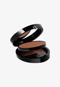 Compact negro circular con un espejo, que contiene un polvo marrón y un compartimento para un pincel; textura suave, logotipo en la parte superior, diseño elegante.