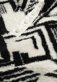 Soft black and white geometric patterned fleece fabric with a white buttoned placket featuring four round buttons.