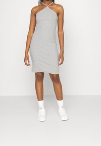 Hame dekolte grå i en bomullsblanding, tettsittende silhuett, kne-lengde, glatt tekstur, parret med hvite joggesko og sokker.