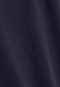 Tissu bleu marine foncé avec une texture tricotée fine et lisse et de subtiles ombres diagonales créant un effet de pli doux.