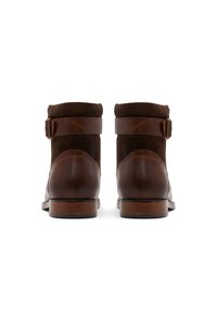 Bruna läderankelboots med en texturerad mocka ovandel, staplad klack och en sidrem med en metallspänne.