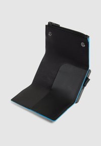 Cartera negra con textura mate, que presenta un compartimento con cremallera y bordes azules en contraste. El interior tiene un acabado liso con ranuras para tarjetas.