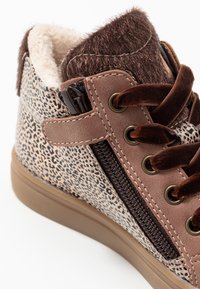 Hnědé tenisky vysokého střihu s zvířecím potiskem a měkkým umělým kožíškem na límci, polstrované uvnitř a s kontrastními hnědými šňůrkami. Boční zip pro snadné obouvání.