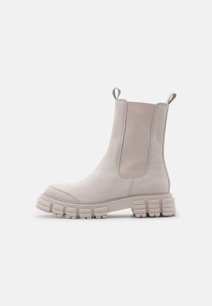 Beige Chelsea-Boot in Knöchelhöhe mit dicker, klobiger Sohle, elastischen Seitenpanelen und Zuglaschen vorne und hinten.