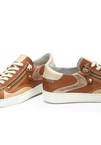 Baskets en cuir marron avec accents en daim beige, fermetures éclair et lacets crème. Semelle texturée légère avec logo sur le côté.