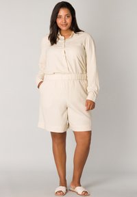 Crème-kleurige overhemd met lange mouwen en een zak, gecombineerd met shorts met elastische taille. Glad materiaal, ontspannen pasvorm en een eenvoudig ontwerp.