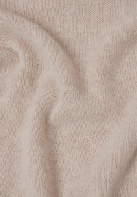 Tissu tricoté doux et rose clair, présentant une texture subtile et des points fins et uniformément répartis. Idéal pour des vêtements ou des accessoires douillets.