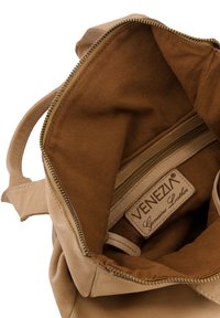 Beiges Lederhandtascheninnere mit beigem Futter, separatem Reißverschlussfach und einem Etikett mit der Aufschrift "Venezia Echtes Leder."