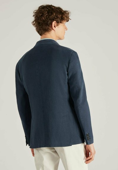 Marineblauwe op maat gemaakte jas van lichtgewicht stof, voorzien van een enkele split aan de achterkant, met knoopsluiting aan de mouwen en een strakke uitstraling.