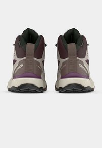 Τα παπούτσια πεζοπορίας Salomon X Ultra 3 διαθέτουν σχεδιασμό σε σκούρο μωβ και μπεζ χρώμα με υφή στη φτέρνα και αναπνεύσιμα διχτυωτά πάνελ για άνεση.