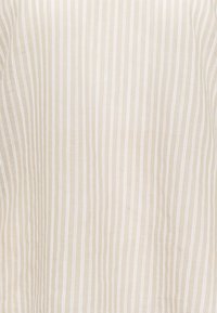 Tissu beige avec de fines rayures verticales blanches, présentant une texture lisse. Le matériau semble léger et respirant.