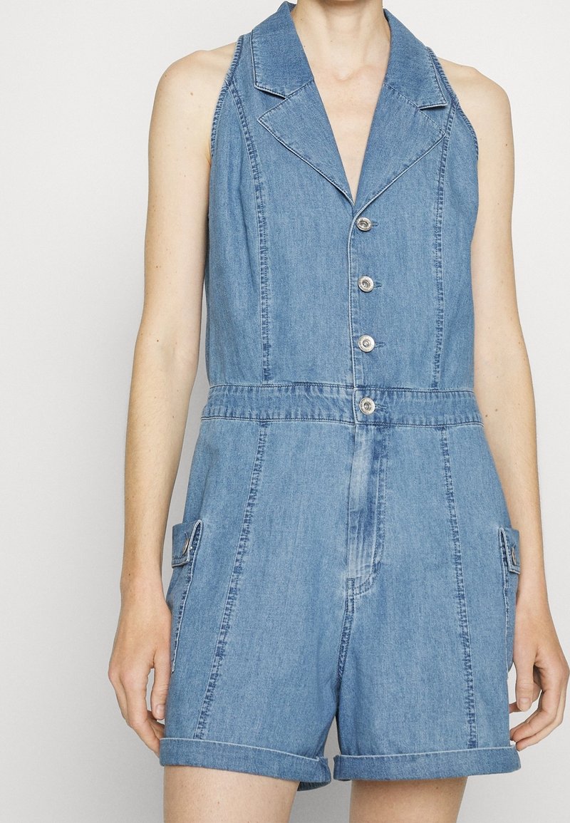 Denim overal s límečkem, pěti knoflíky, dvěma bočními kapsami, ohrnutými rukávy a světle modrou barvou s hladkou texturou.
