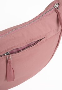 Borsa in tessuto rosa con una forma curva, dotata di una cerniera argentata e un piccolo tirazip texturizzato. Tasca interna visibile. Texture liscia.