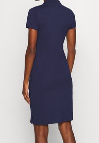 Robe polo bleu marine à manches courtes, avec un col, des fentes sur les côtés et une silhouette ajustée, fabriquée en un mélange de coton doux.