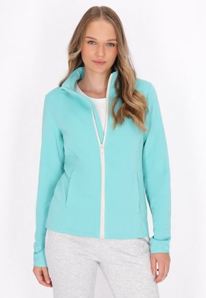 Lichtblauwe zip-up jack met twee zijzakken, gemaakt van een gladde stof. Heeft een hoge kraag en een contrasterende witte rits.