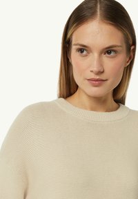 Beige Strickpullover mit rundem Halsausschnitt und gerippten Bündchen, der ein strukturiertes Muster und eine weiche Oberfläche aufweist. Fällt angenehm am Körper.
