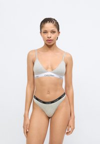 Γκρι βαμβακερό μπουστάκι Calvin Klein με λεπτές τιράντες· ταιριαστό στρινγκ με μαύρη ζώνη μέσης με λογότυπο και διακριτικό ριγέ μοτίβο.