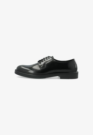 Zapato de vestir de hombre de cuero negro pulido con cordones al frente y tacón bajo, mostrado de perfil lateral sobre fondo blanco.