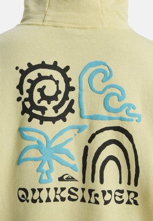 Gele capuchontrui met vier patronen: zwarte spiraal, blauwe golf, blauwe palmboom en een boog, met de tekst "QUIKSILVER" in het zwart.