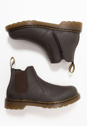 Bottes Chelsea en cuir marron avec panneaux latéraux élastiques, coutures jaunes, semelles épaisses translucides et fermeture éclair latérale sur une botte.