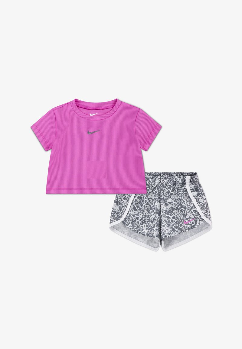 Rožinis banguotas trumpas marškinėlis su trumpomis rankovėmis, derinamas su pilkomis šortais, turinčiais baltas detales ir abstraktų raštą. Abiejuose drabužiuose yra Nike logotipas.