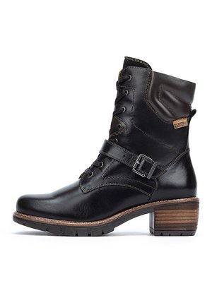 Black leather ankle boot with a lace-up front, a buckled strap, and a wooden block heel. Features a padded collar and subtle stitching.
