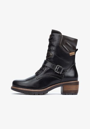 Schwarze Leder-Ankle-Boots mit Schnürung vorne, einem geschnallten Riemen und einem Blockabsatz aus Holz. Verfügt über einen gepolsterten Schaft und dezente Nähte.
