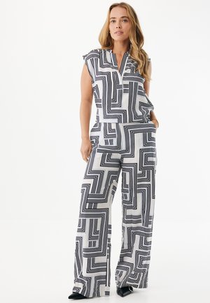 Tuta a motivo bianco e nero con design senza maniche, caratterizzata da linee geometriche e pantaloni a gamba larga, realizzata in tessuto leggero.