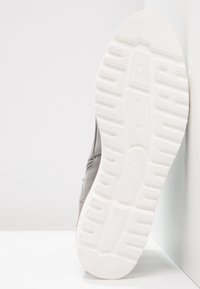 Baskets grises avec une tige texturée, dotées d'une semelle en caoutchouc blanche à la semelle à motif et d'un design minimaliste.