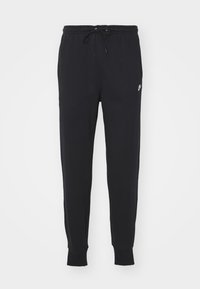 Pantalones de chándal negros con cintura ajustable, piernas estrechas, puños elásticos y un pequeño logotipo blanco en el lado izquierdo. Material de algodón.